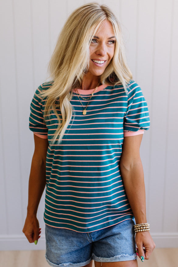 Woman wearing a striped shirt and denim shorts against a plain background