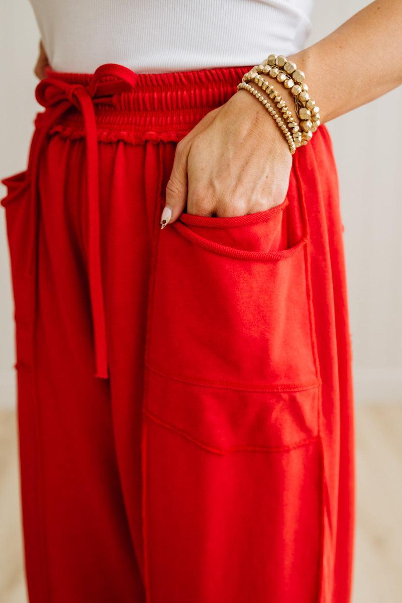 Red pants with a pocket and a white top, on a neutral background