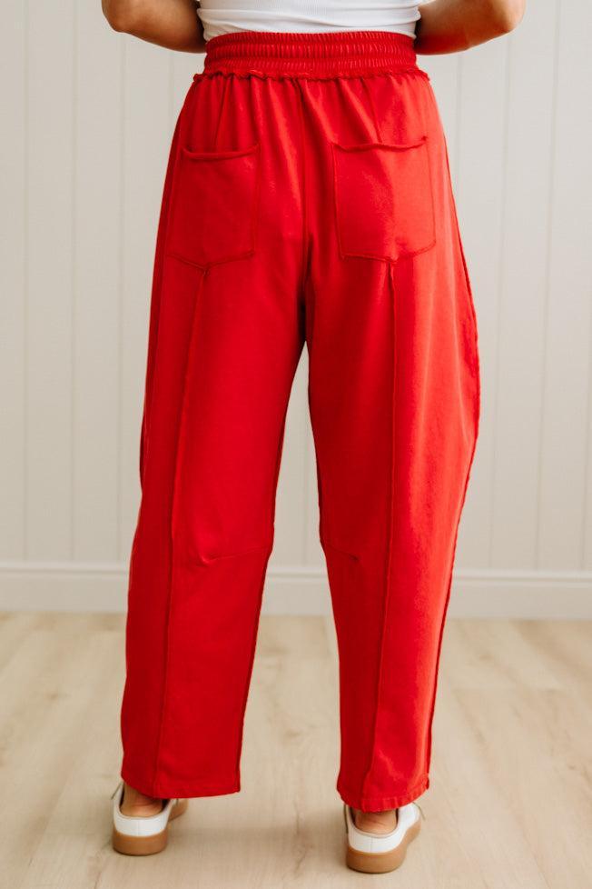 Red pants worn by a person on a light wooden floor with a white wall background