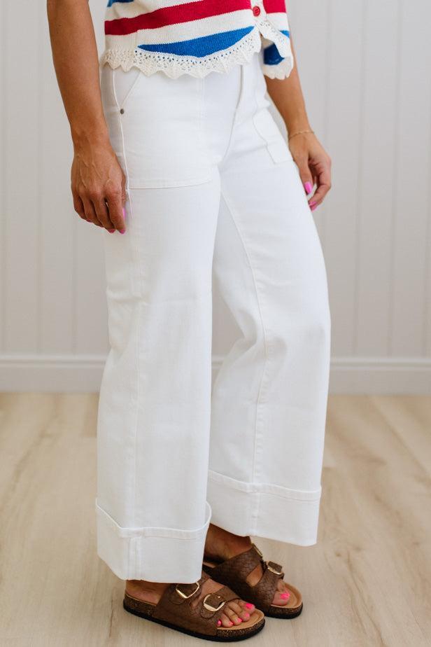 Person wearing white pants and a colorful top on a plain background