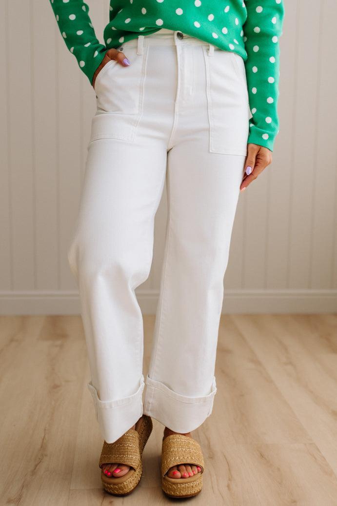 Woman wearing white jeans with square patch pockets and wide cuff at ankle.