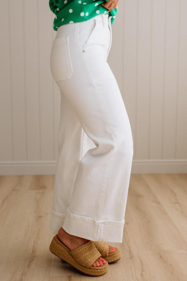 Woman wearing white jeans with square patch pockets and wide cuff at ankle.