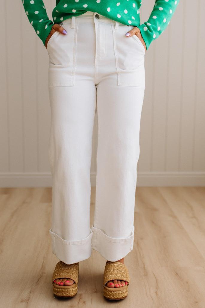 Woman wearing white jeans with square patch pockets and wide cuff at ankle.