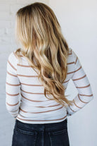 Person wearing a striped long-sleeve shirt with a plain background
