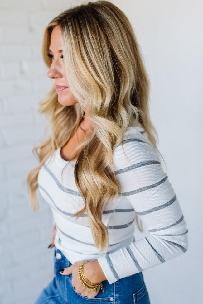 Woman wearing a striped sweater and blue jeans against a light background