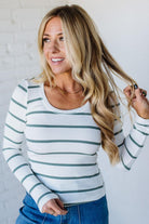 Woman wearing a striped long-sleeve shirt and blue jeans against a white background