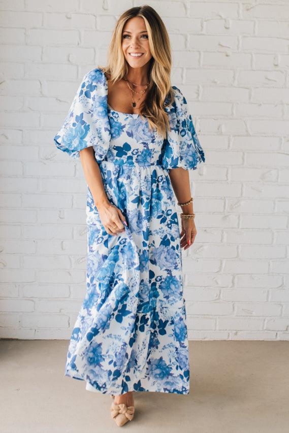 Blonde Woman Wearing a Floral Print Puff Sleeve Maxi Dress in Blue and White.