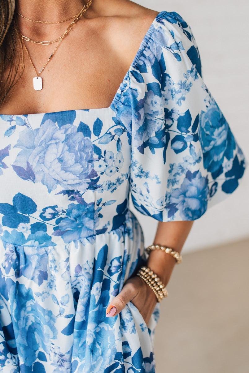Blonde Woman Wearing a Floral Print Puff Sleeve Maxi Dress in Blue and White.