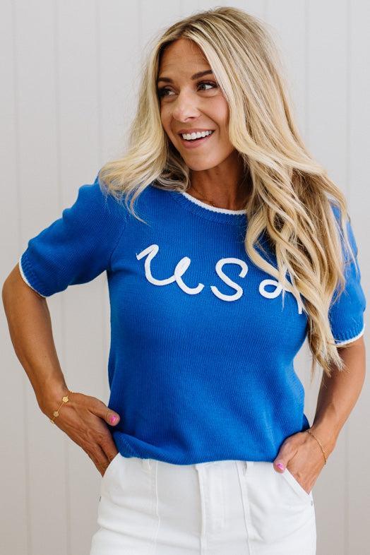 Woman wearing a blue sweater with 'USA' text against a white background