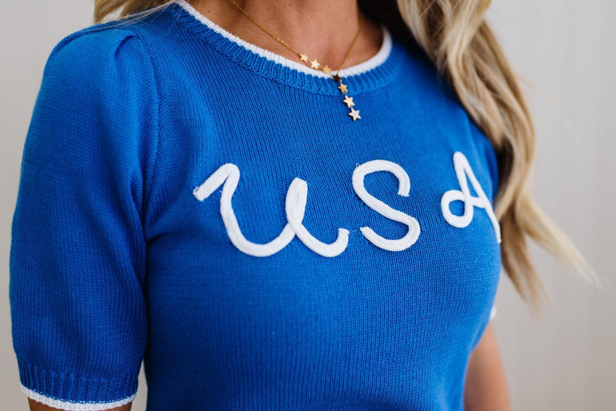 Blue sweater with 'USA' text worn by a person