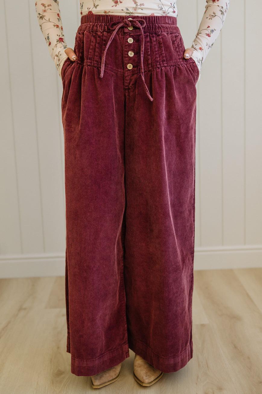 Person wearing maroon corduroy pants with a white wall background