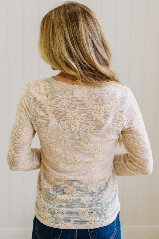 Blonde Woman Wearing A Floral Embroidered Stretch Lace Long Sleeve Top with Dark Jeans and Light Brown Belt.