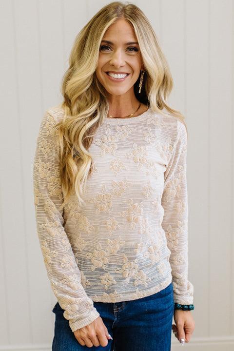 Blonde Woman Wearing A Floral Embroidered Stretch Lace Long Sleeve Top with Dark Jeans and Light Brown Belt.