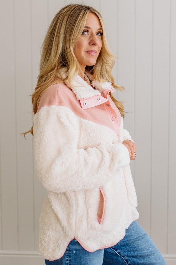 Woman wearing a white and pink jacket with a neutral background