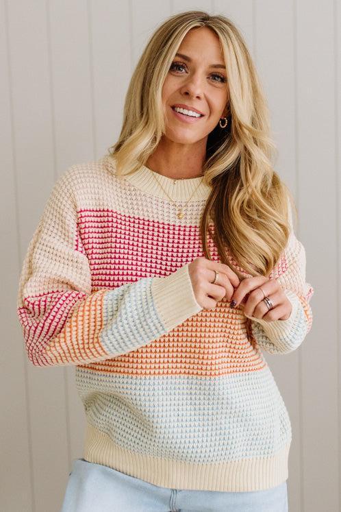 Woman wearing a colorful patterned sweater against a neutral background