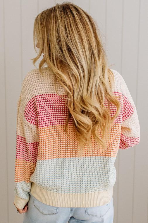 Person wearing a colorful sweater with a neutral background