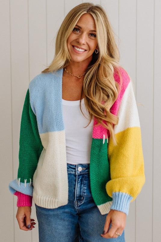Woman wearing a colorful cardigan with a white wall background