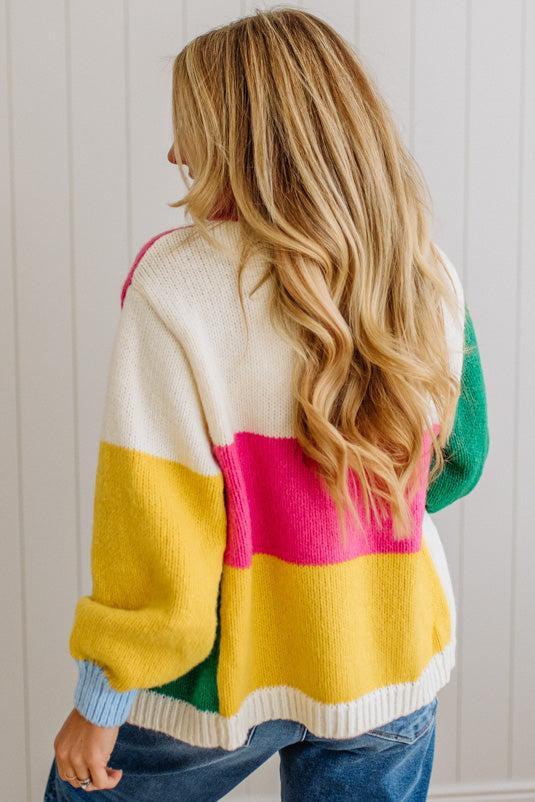 Person wearing a colorful striped sweater against a white wall