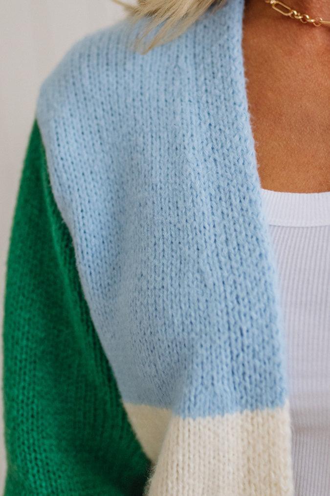 Color-blocked sweater with green, blue, and white sections.