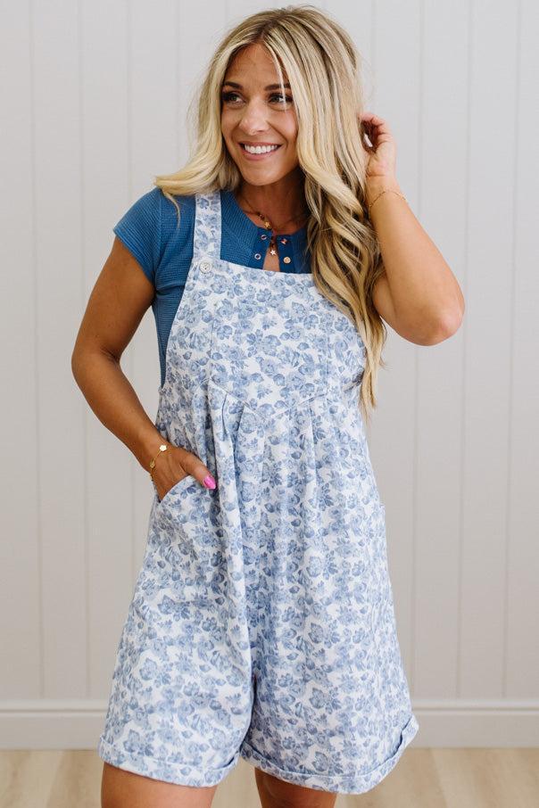 Woman wearing a blue floral romper with a plain background