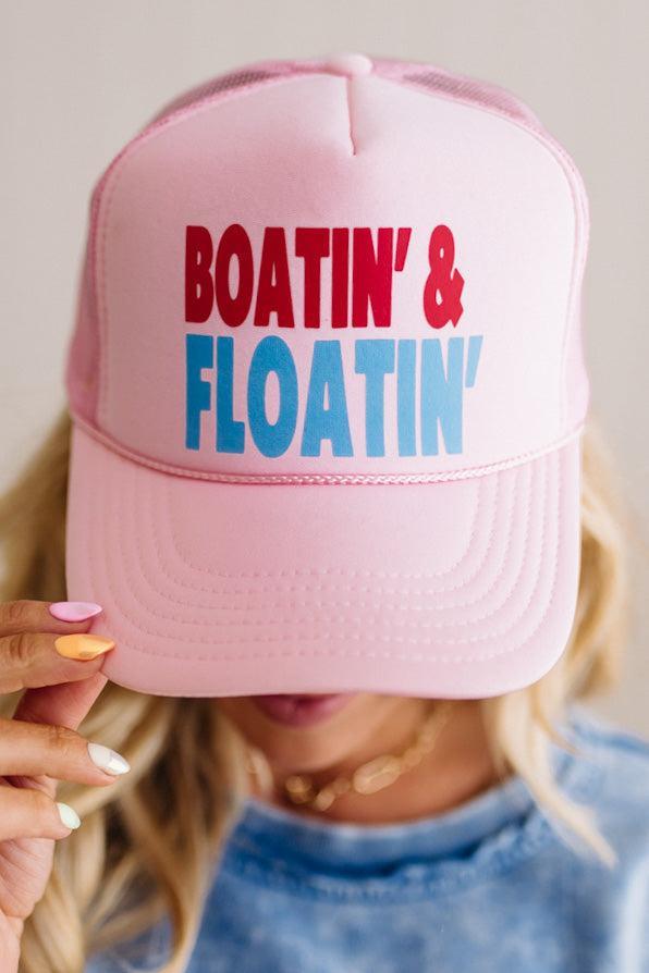 Pink cap with 'Boatin' & Floatin' text held by a person