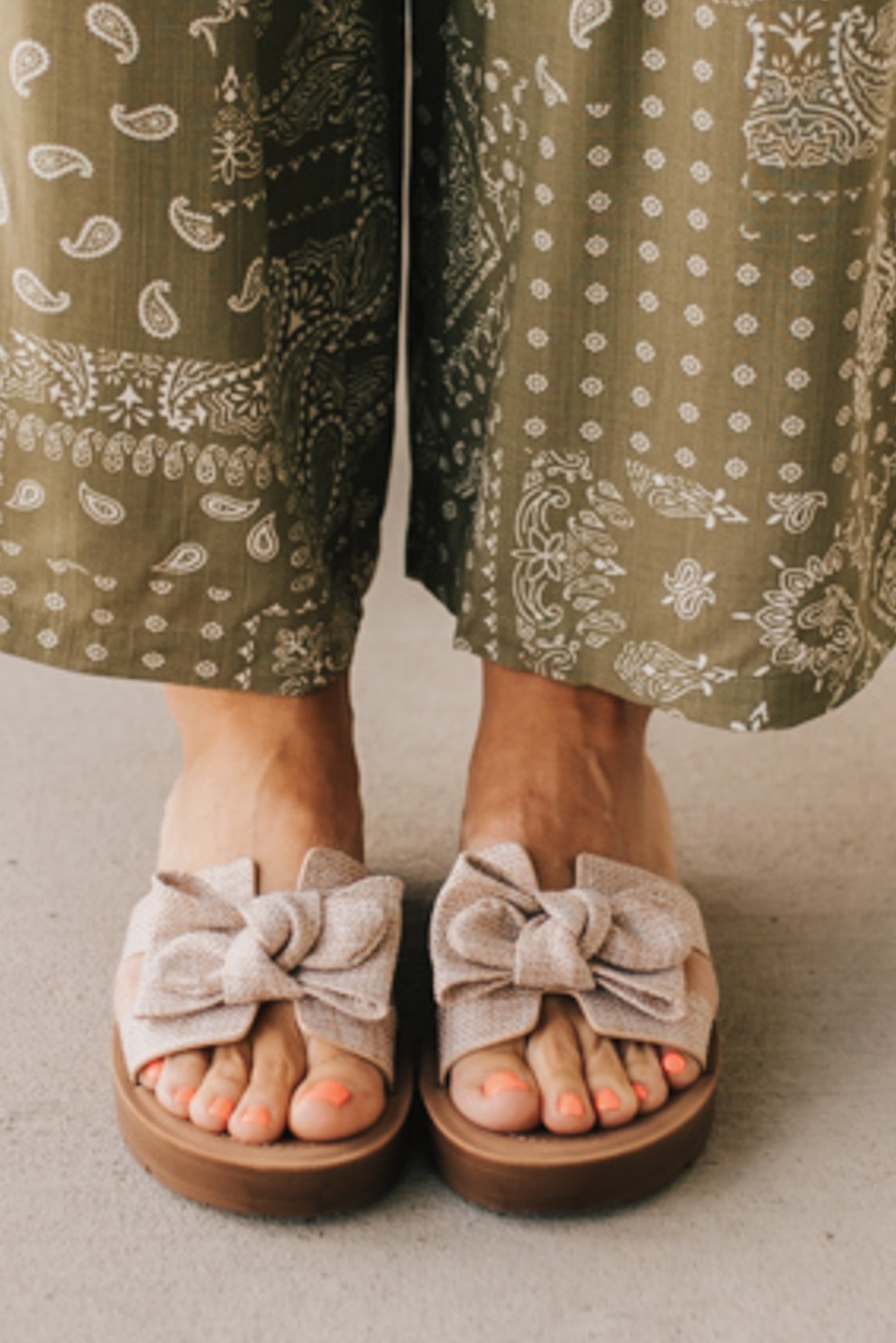 Woman wearing Bow Top Linen Slide Sandals with Taupe Linen Texture.