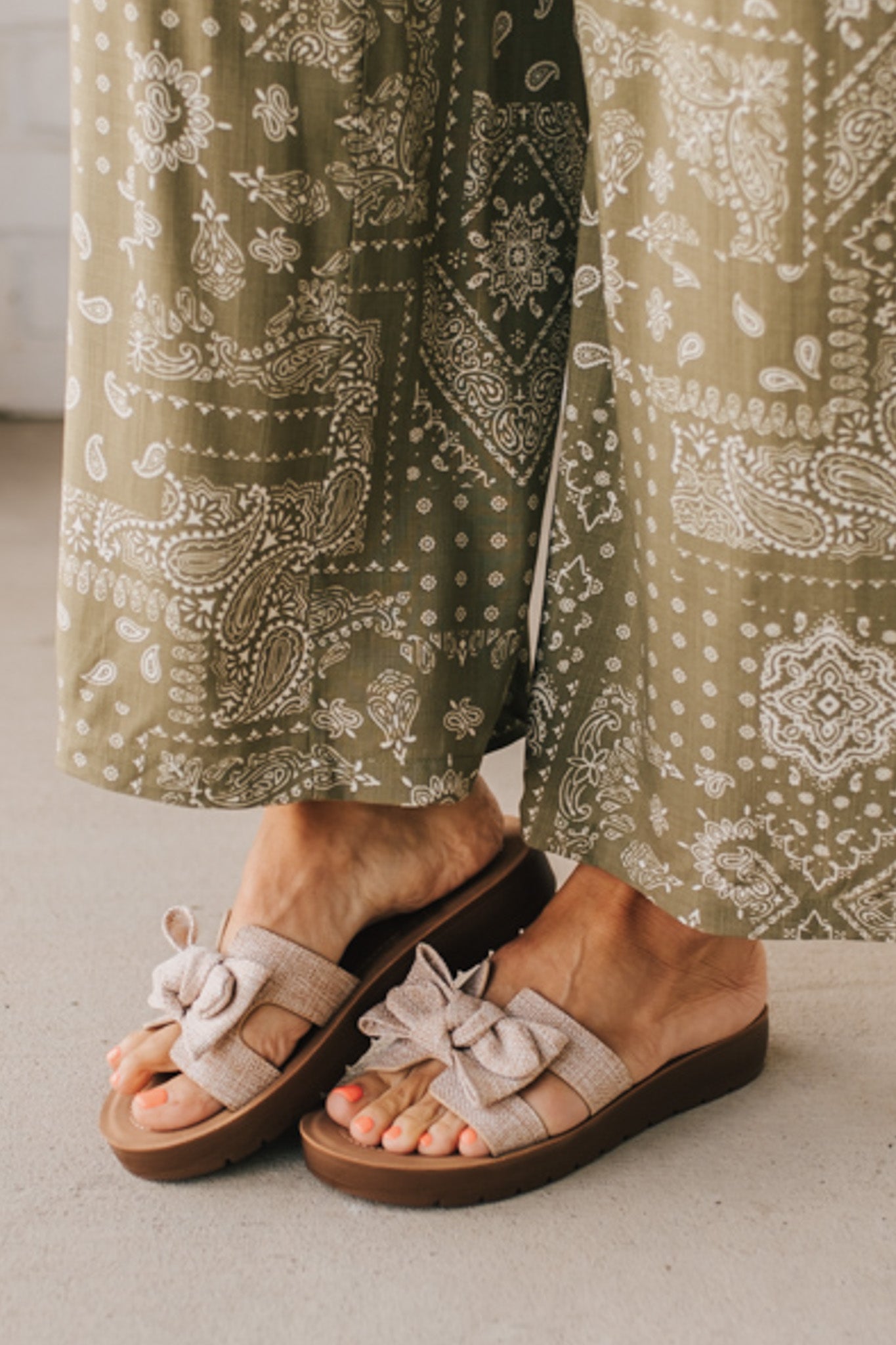 Woman wearing Bow Top Linen Slide Sandals with Taupe Linen Texture.