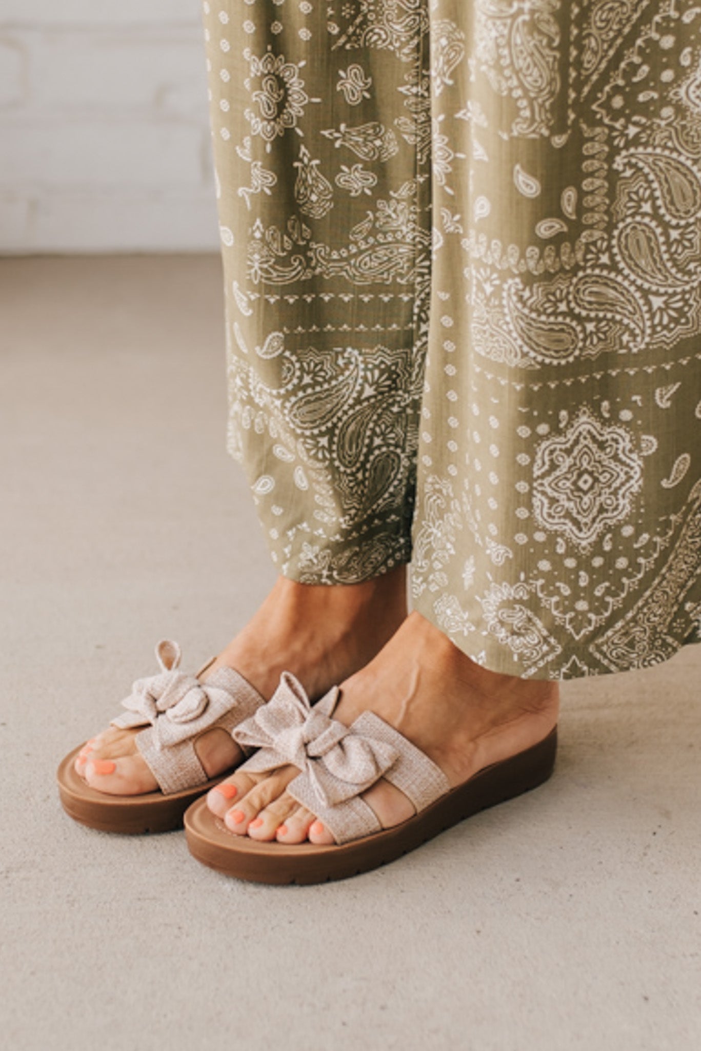Woman wearing Bow Top Linen Slide Sandals with Taupe Linen Texture.