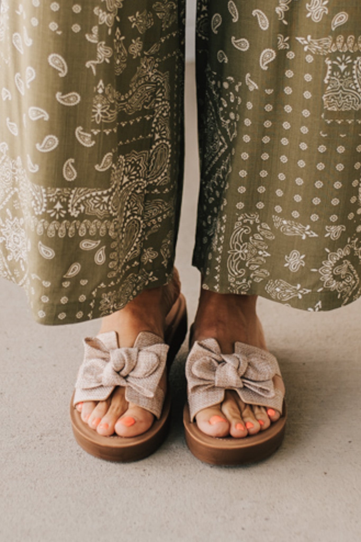Woman wearing Bow Top Linen Slide Sandals with Taupe Linen Texture.