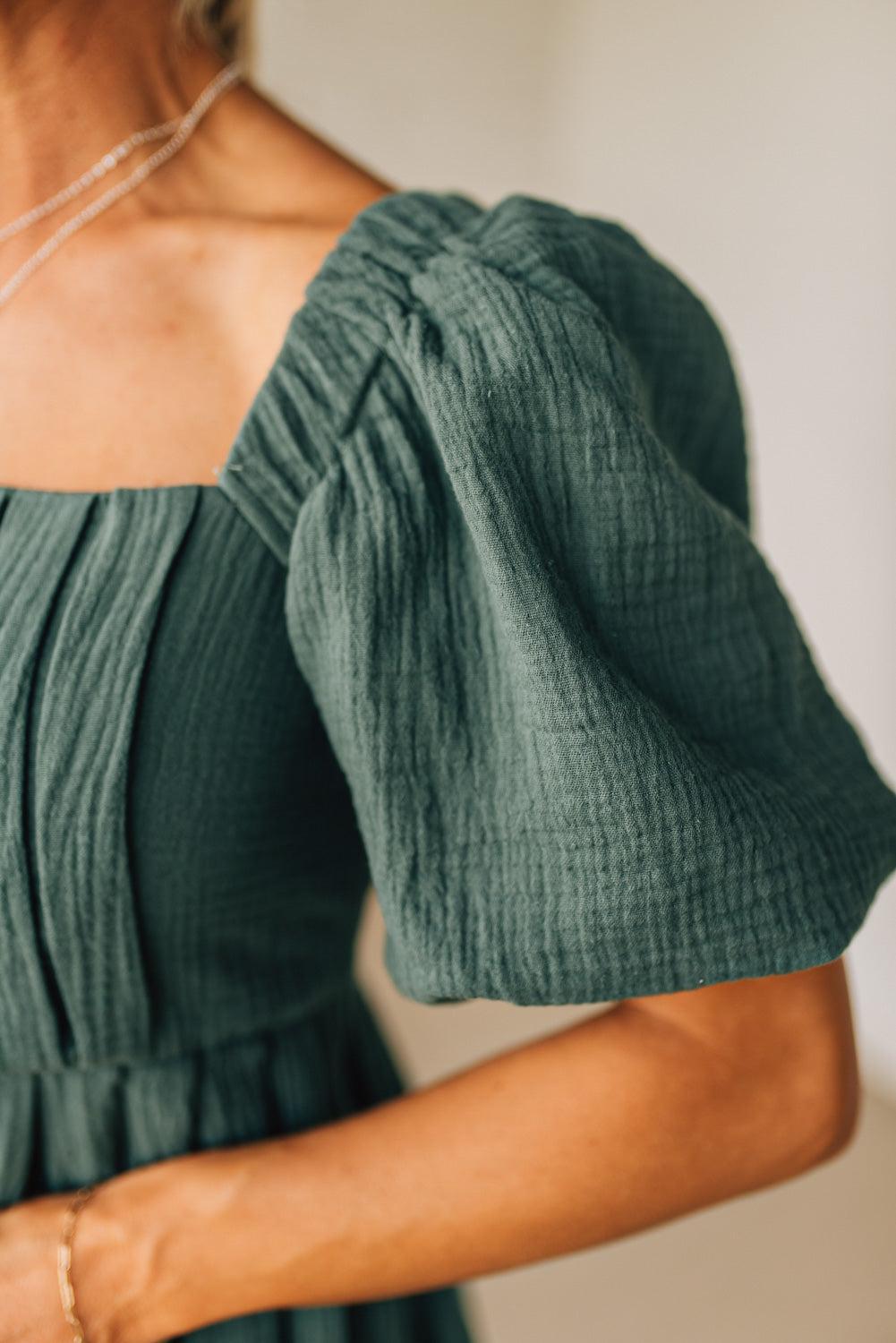 Green off-shoulder top with textured sleeves on a neutral background