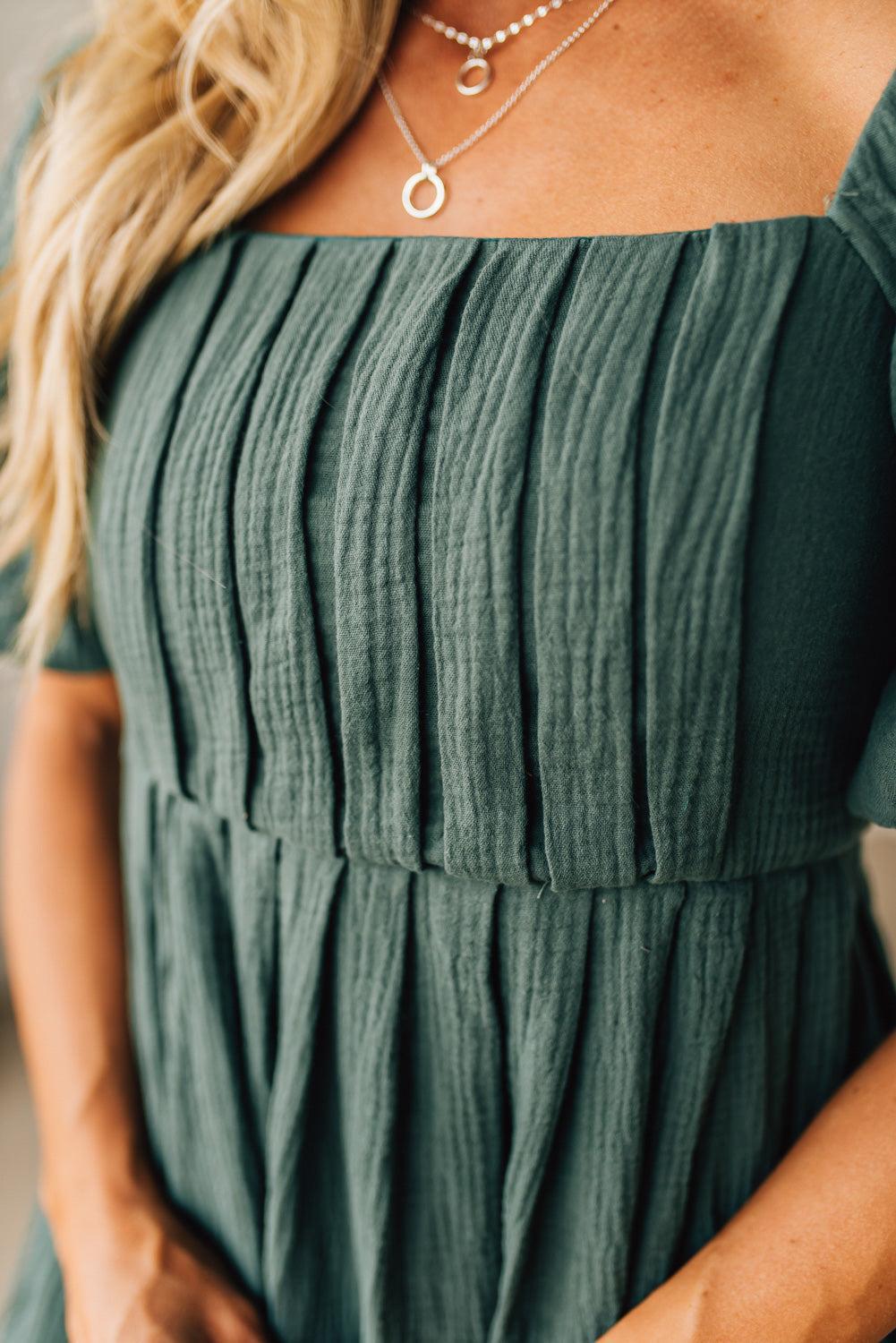 Green off-shoulder dress worn by a person with visible jewelry.