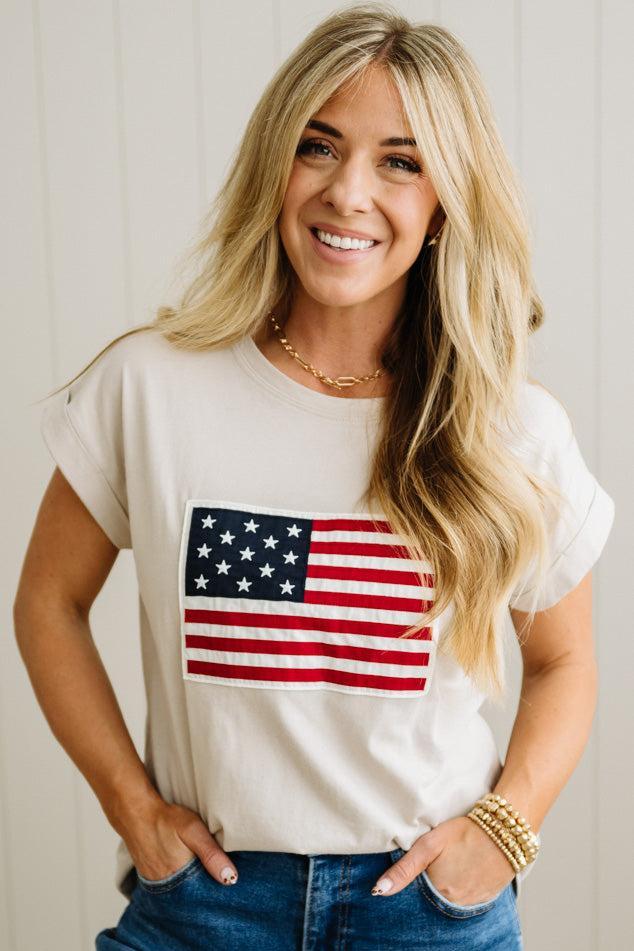 Woman wearing a white t-shirt with an American flag design against a plain background