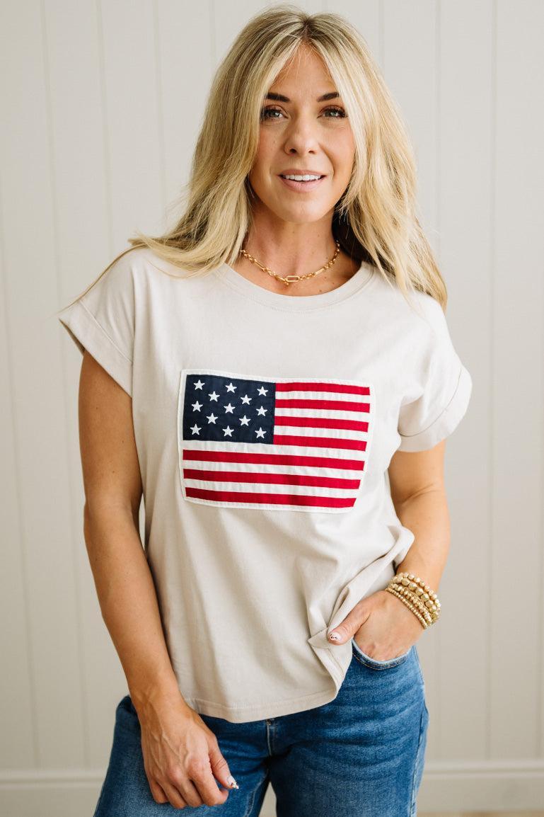Woman wearing a white t-shirt with an American flag design against a plain background