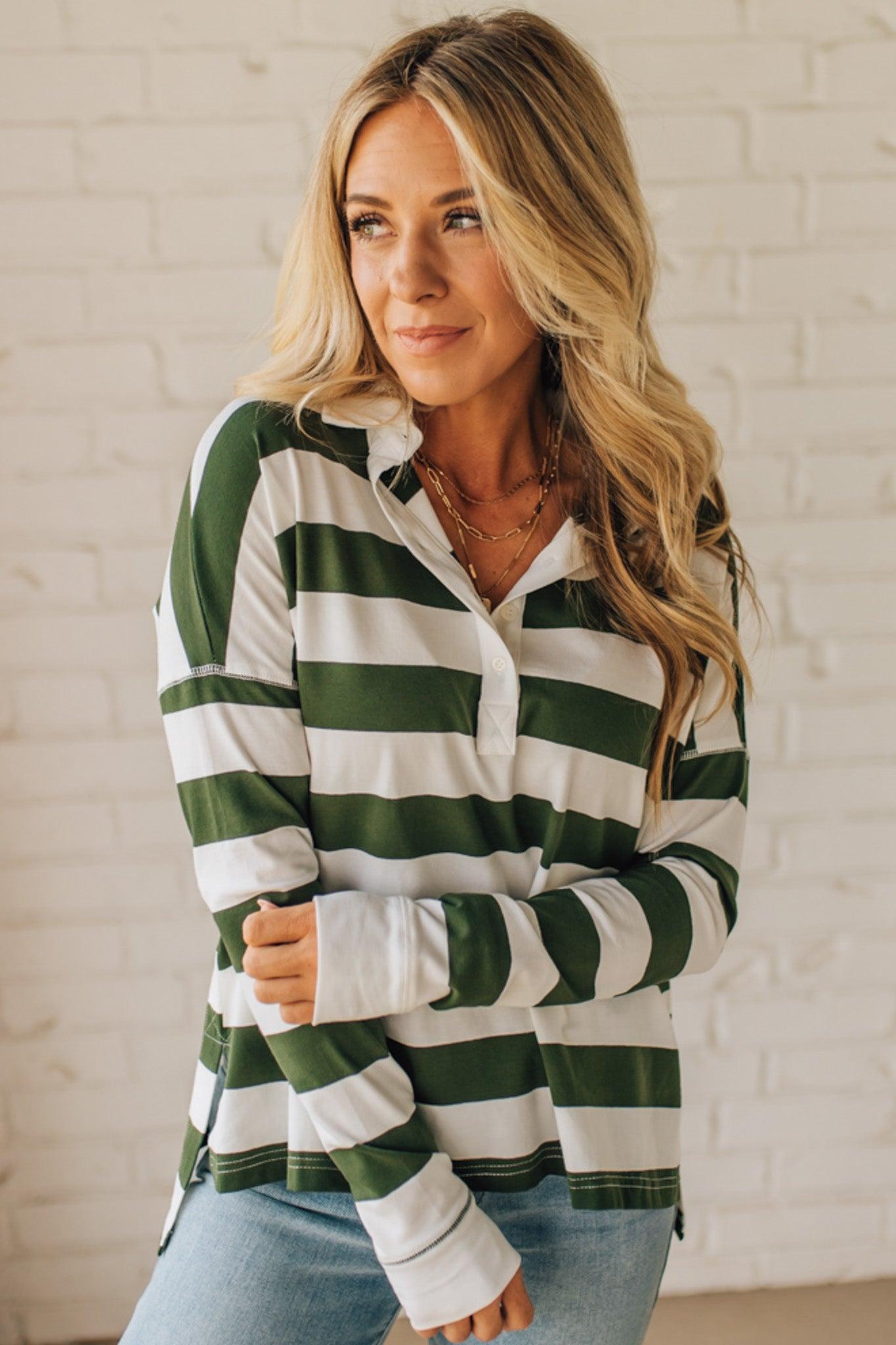 Woman wearing a green and white striped shirt against a white brick wall.