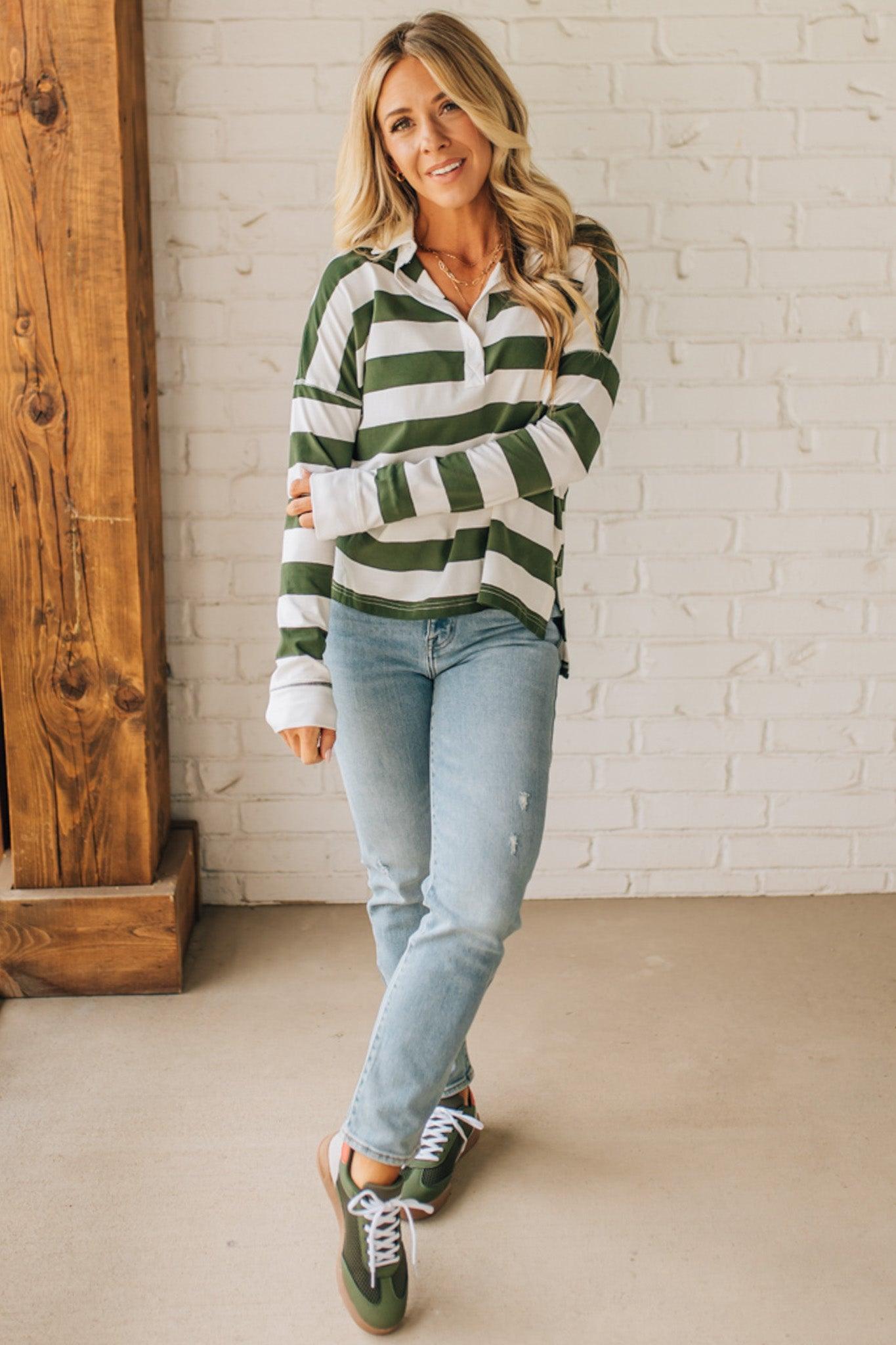 Woman wearing a green and white striped shirt with light blue jeans indoors.