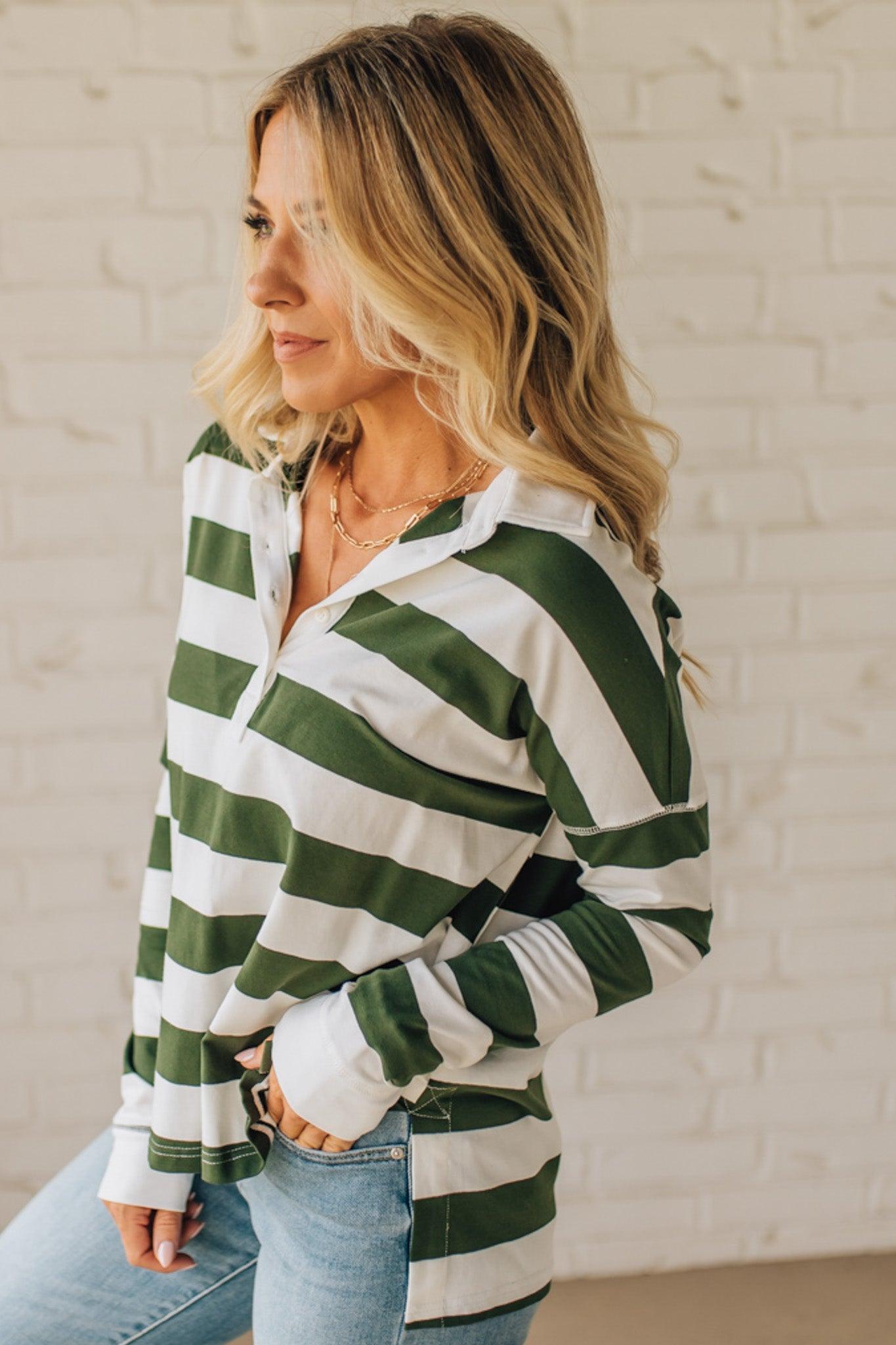 Woman wearing a green and white striped shirt against a white brick wall.