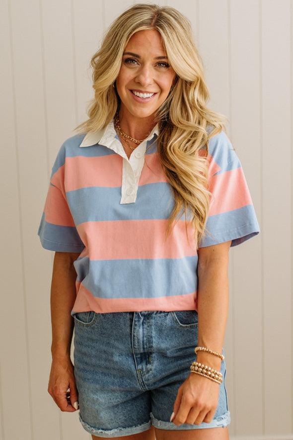 Woman wearing a striped shirt and denim shorts against a neutral background