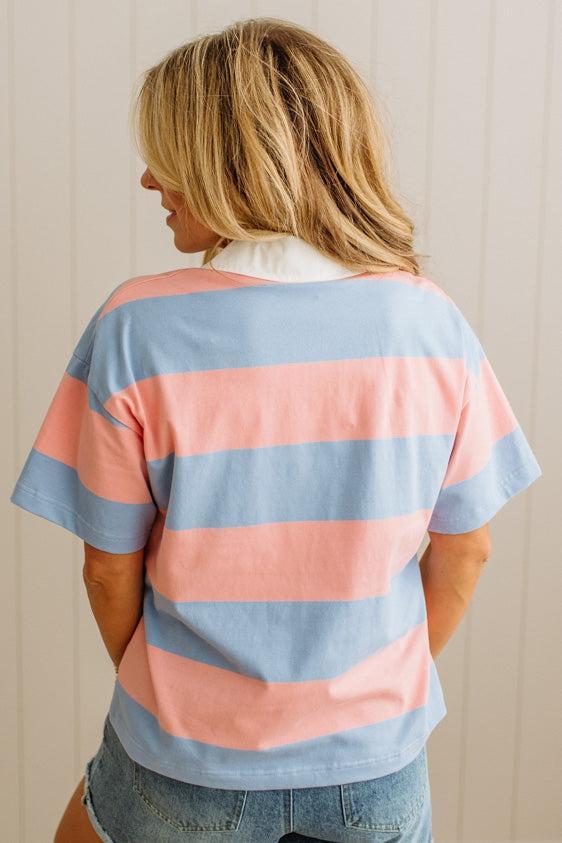 Person wearing a striped shirt with pink and blue horizontal stripes.