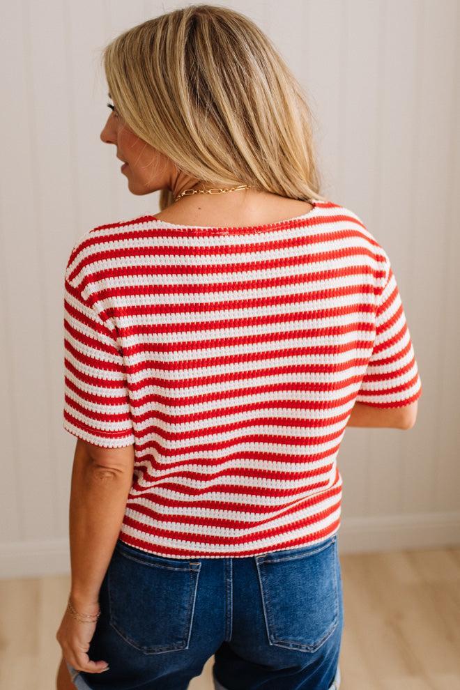 Woman wearing a red and white striped shirt with blue jeans against a neutral background
