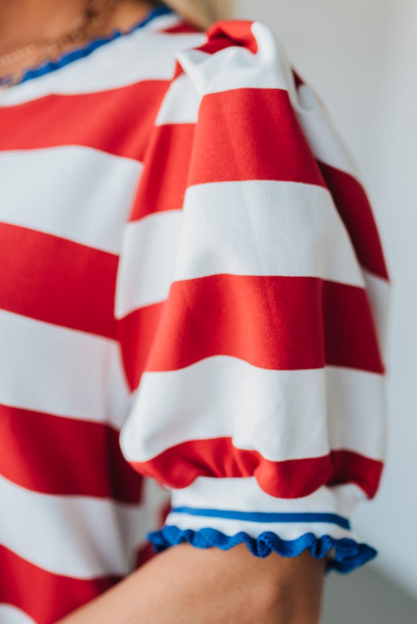 Blonde Woman Wearing a Ruffle Ribbed Detail Stripe French Terry Mini Dress with bright red thick stripes.