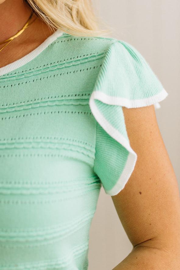 Mint green top with white trim on a neutral background