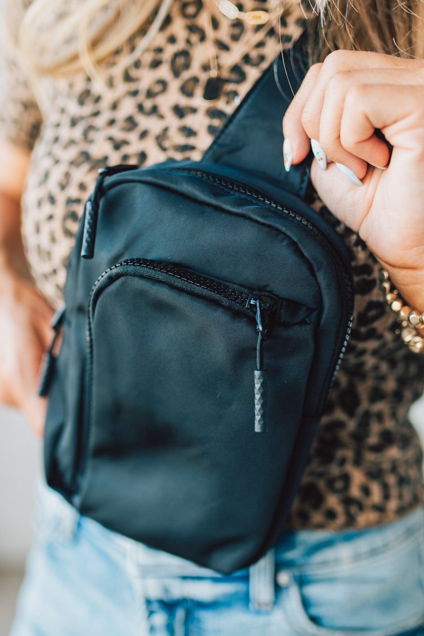 Blonde woman in a leopard tee shirt wearing a black Essential Nylon Crossbody bag.