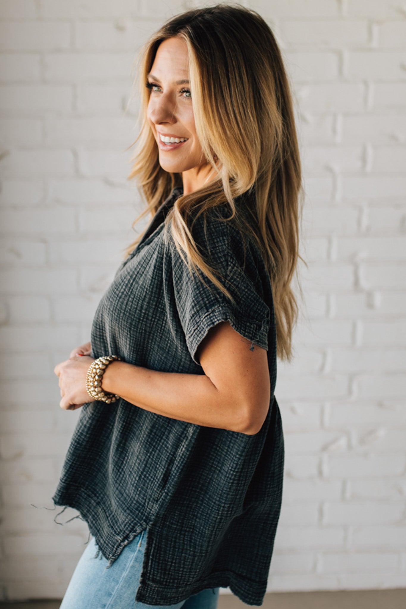 BLONDE WOMAN WEARING A WASHED DOUBLE GAUZE 3/4 BUTTON HENLEY NECK SHIRT.