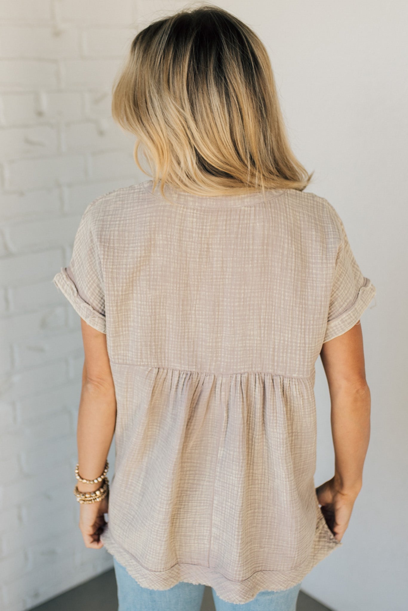BLONDE WOMAN WEARING A WASHED DOUBLE GAUZE 3/4 BUTTON HENLEY NECK SHIRT.