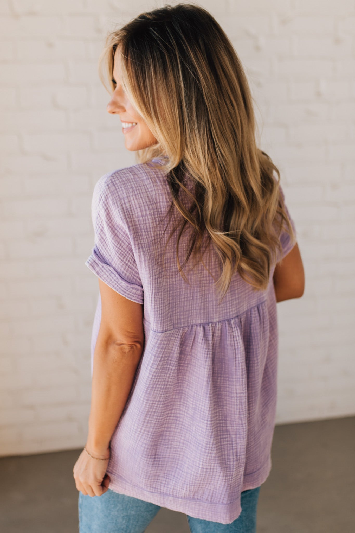 BLONDE WOMAN WEARING A WASHED DOUBLE GAUZE 3/4 BUTTON HENLEY NECK SHIRT.