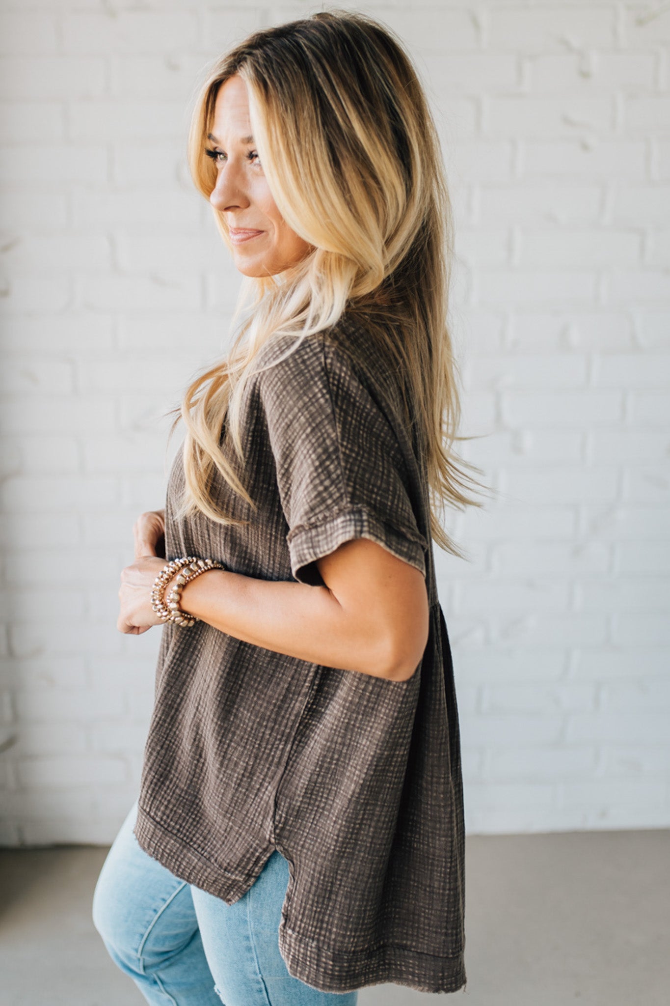 BLONDE WOMAN WEARING A WASHED DOUBLE GAUZE 3/4 BUTTON HENLEY NECK SHIRT.