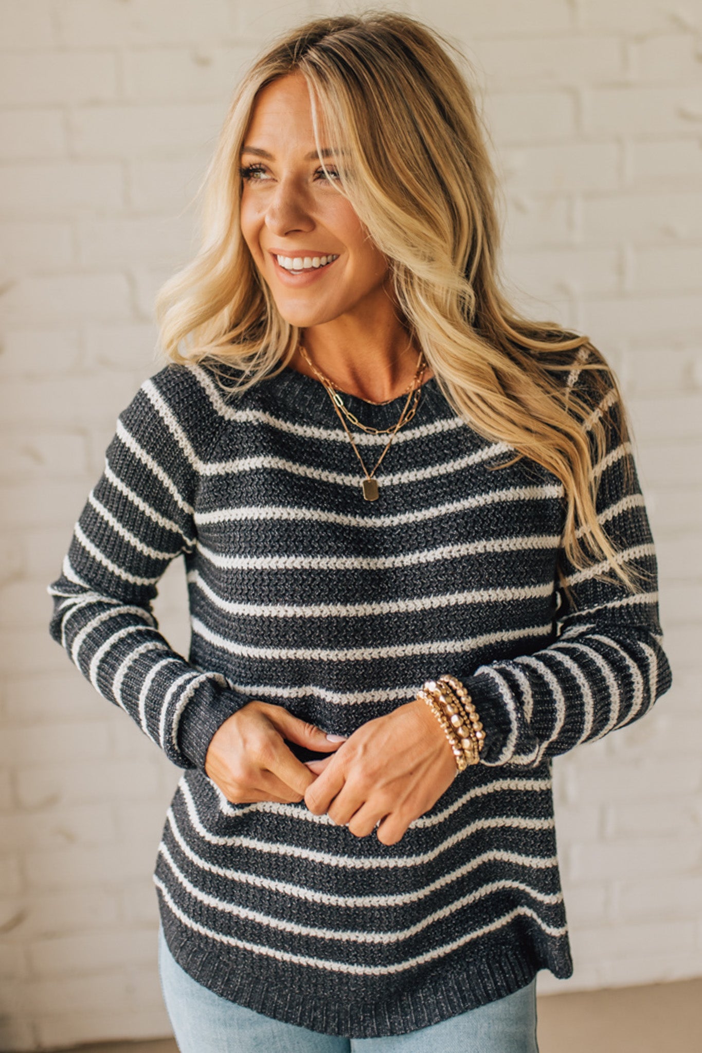 BLONDE WOMAN WEARING A CREW NECK, LONG RAGLAN SLEEVE, CURVED HEM, MINI WAFFLE STRIPED PULLOVER SWEATER