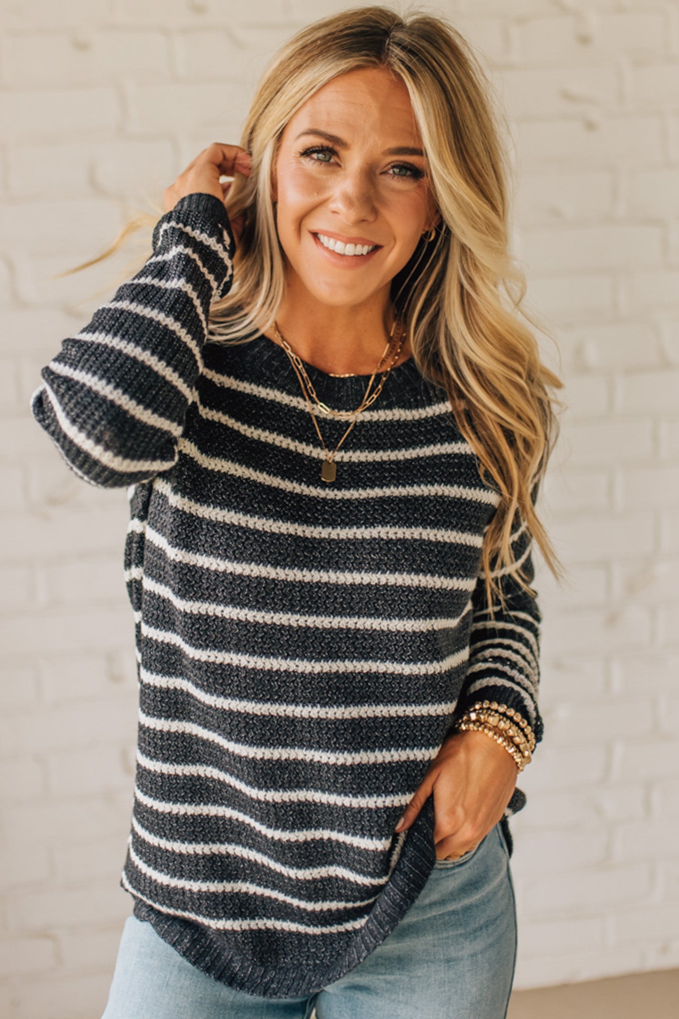 BLONDE WOMAN WEARING A CREW NECK, LONG RAGLAN SLEEVE, CURVED HEM, MINI WAFFLE STRIPED PULLOVER SWEATER