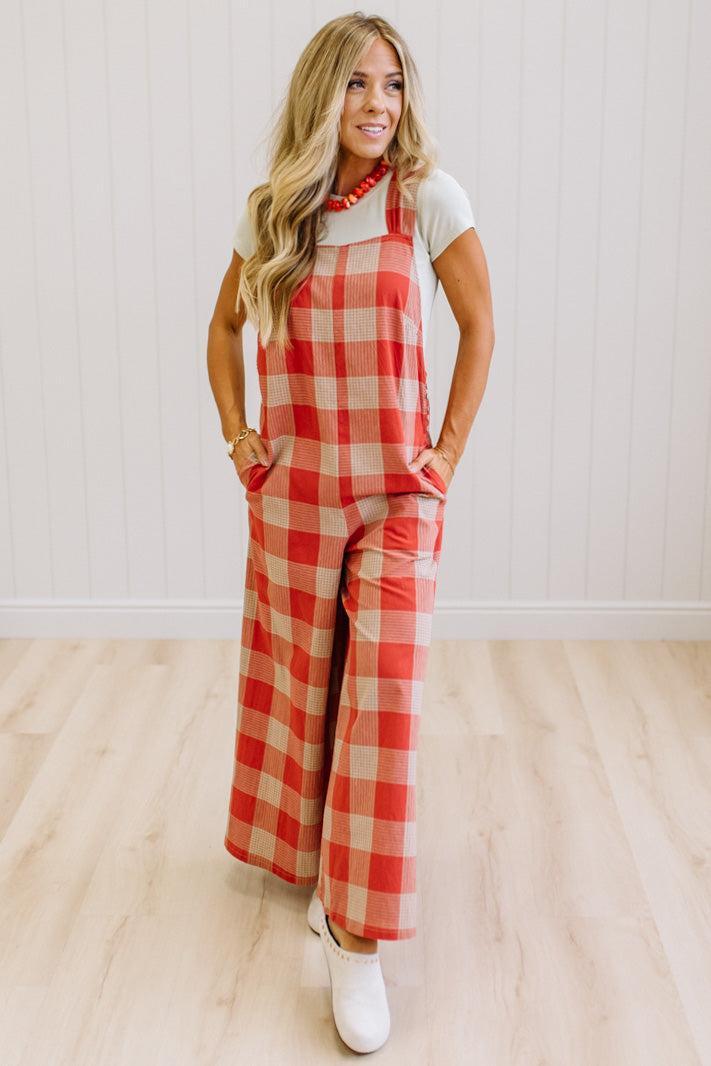 Blonde woman in a studio with light wood floors and a light backdrop, wearing a tee-shirt and latte/orage wide leg jumpsuit.