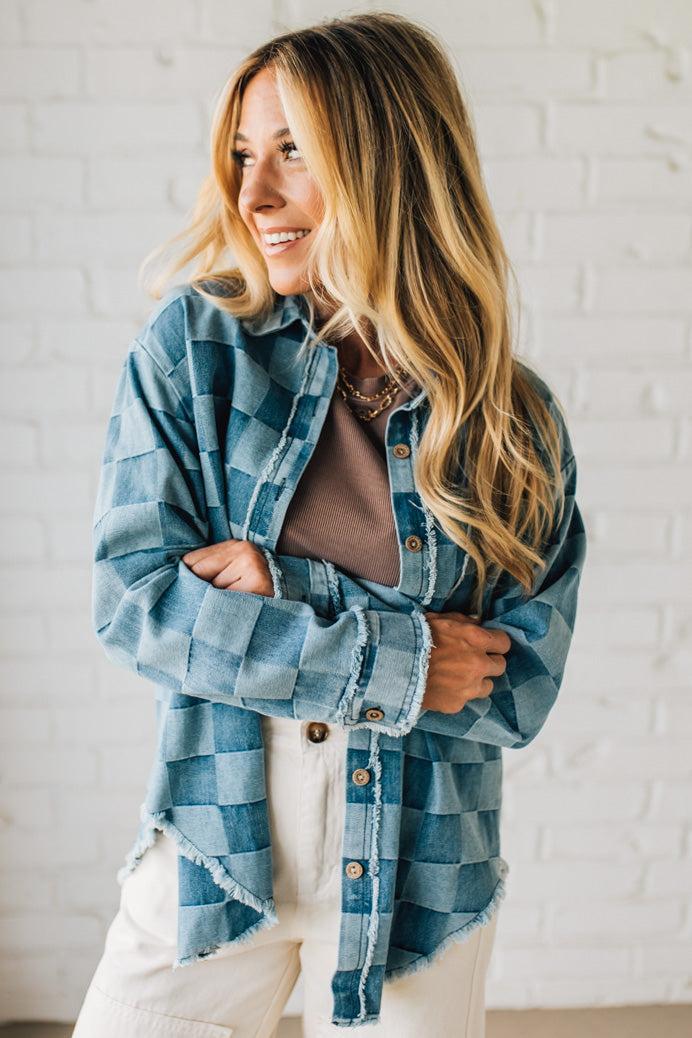 Woman wearing a blue plaid shirt against a white brick wall